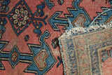 Close-up of antique Lilihan rug's dusty blush pile showing wear, tattered fringe, and woven foundation.