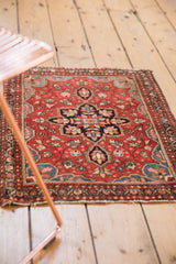 Intricate cherry red Farahan Sarouk rug with navy medallion, floral tendrils, and tattered edge.