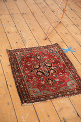 Vintage Farahan Sarouk rug corner with cherry red field, intricate floral border, and visible tatter.