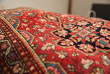 Intricate floral outlining and navy finial motif on the cherry red vintage Persian rug.