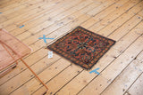 Angled view of antique Lilihan square rug, bold floral motifs, intricate borders, and tattered edges.