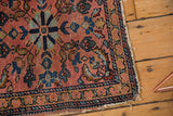 Intricate navy and rose floral border with tattered edge on an antique Lilihan rug.