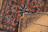 Antique Lilihan rug folded back, showing dusty rose floral pile, detailed borders, and reverse weave.
