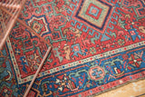Geometric motifs in cherry red, sky blue, and oxidized green on an antique Karaja pile.