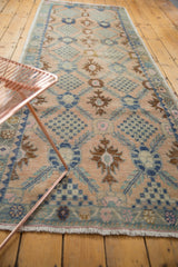 Distressed Oushak runner with pale blush ground, faded blue lattice motif, and intricate floral bouquets.