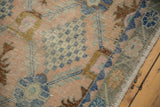Worn blush, blue, bronze Oushak rug with faded lattice and intact selvage.