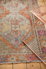 Distressed Turkish Oushak runner, highlighting worn pile and rust, hot pink stepped patterns.