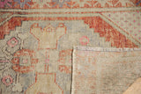 Close-up of distressed vintage Oushak pile with rust, pink, and ivory tones, revealing reverse.