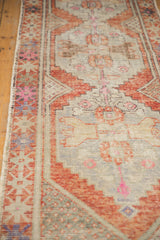 Distressed Oushak runner border, with faded rust, ivory, and hot pink geometric patterns.