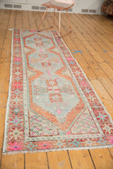 Distressed Oushak runner corner, showing fringe and geometric motifs in rust, pink, and ivory.