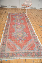 Distressed vintage Oushak runner end, showing checkered spandrels, serrated medallion, and cinnabar red and oxidized silver pile.