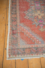 Bottom corner of a distressed Oushak runner, with faded cinnabar spandrels, oxidized silver border, short fringe.