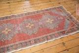 Distressed vintage Oushak runner shows faded cinnabar red field with serrated gray, beige motifs.