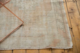 Distressed Oushak runner corner, pale sand geometric pattern, and visible pile wear.