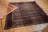 Antique Belouch rug detail with geometric channels, saffron blossoms, and worn edge.