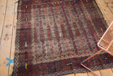 Antique Belouch rug showcasing geometric border and field's vertical blossomed flower channels with patina.