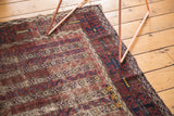 Antique Belouch rug's detailed border with geometric and floral motifs, showing time-softened navy, red, brown.