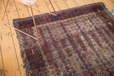 Antique Belouch rug’s striped channels and blossomed flowers in brown, navy, red, and ivory.