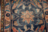 Curvilinear pale blush rose palmette on dark indigo blue antique Lilihan rug, showing wear.
