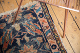 Antique Lilihan rug corner, dark indigo field, blush rose border, visible knot wear, tattered fringe.