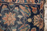 Corner close-up of antique Lilihan rug, indigo field, blush rose florals, visible wear, and tatter.