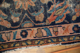 Antique Lilihan rug corner detail: indigo field, blush rose border, tattered fringe, exposed foundation.