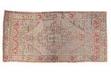 Distressed Oushak runner with faded ivory, cinnabar red, and slate blue geometric medallion.