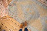 Distressed Oushak rug corner with diamond medallion and spandrel in saffron and slate.