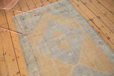 Even wear on a distressed Oushak rug's pile, showing muted saffron yellow and slate blue tones.