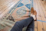Distressed low pile on a vintage Oushak runner with blush field and blue serrated medallion.