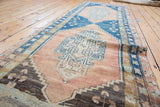 Blush field, blue serrated medallion, and low pile texture on a distressed Oushak runner.