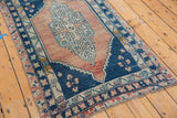 Blush and charcoal blue distressed Oushak runner end, showing fringe and floral border motifs.