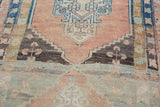 Distressed Oushak runner with serrated medallion, blush, charcoal, seafoam, low pile.