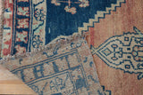Distressed blush pile and blue geometric patterns on the woven back of an Oushak rug runner.