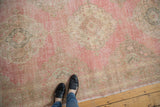 Faded pink and neutral tones of a distressed vintage Sparta rug runner with medallions.