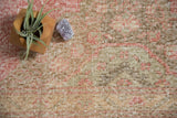 Distressed texture of bubblegum pink and pale bronze Turkish Sparta runner, showing even wear and visible foundation.