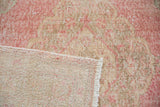Distressed vintage Sparta rug showing worn pink and neutral pile, woven foundation, and fringe.