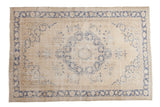 Faded indigo blue medallion and floral motifs on a distressed vintage Oushak rug.