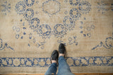 Distressed Oushak carpet featuring faded denim indigo floral motifs on an ivory field.
