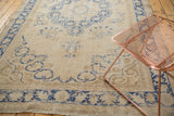 Distressed Oushak rug with denim blue scrolling florals and corner spandrel.