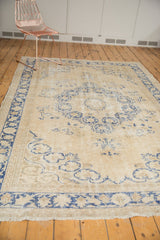 Low pile distressed vintage Oushak rug featuring denim indigo scrolling florals on an ivory field.