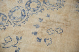 Distressed Oushak pile texture with worn indigo blue floral design, antique ivory.