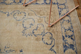 Distressed vintage Oushak rug detail with faded denim blue scrolling motifs on antique ivory.