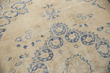 Faded denim blue floral motifs and even wear on the distressed ivory Oushak rug.