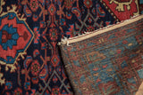 Vintage Dargezine rug's rich navy and red pile, folded to reveal its woven back and fringe.