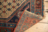 Antique Kurdish Hamadan rug detail: lattice motif, foundation showing, and tattered fringe.