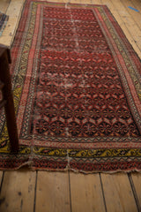 Antique Malayer rug runner's tattered end, displaying minor splits and patterned border.