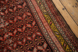 Intricate red serrated leaf motifs on dark ground, bordered by geometric saffron and ivory bands.