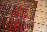 Tattered end of vintage Malayer runner, revealing wear, bright red field, and saffron border.