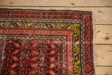 Corner of antique Malayer runner, showing red serrated and saffron scroll borders with fringe.